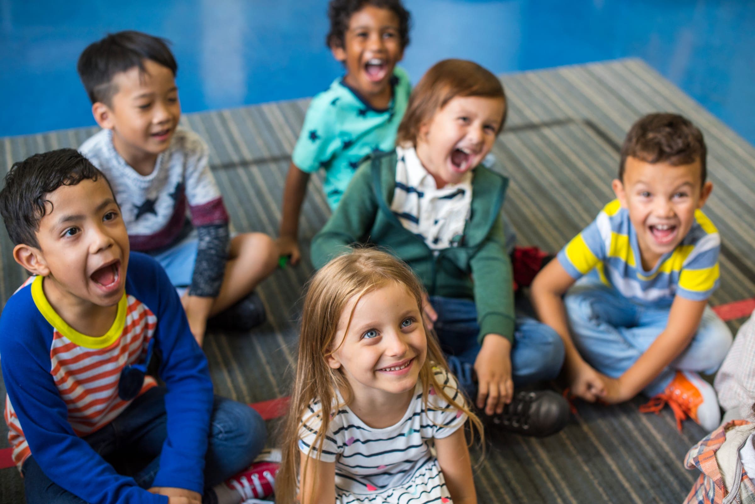 Lachende kinderen zitten samen op de vloer van een klaslokaal