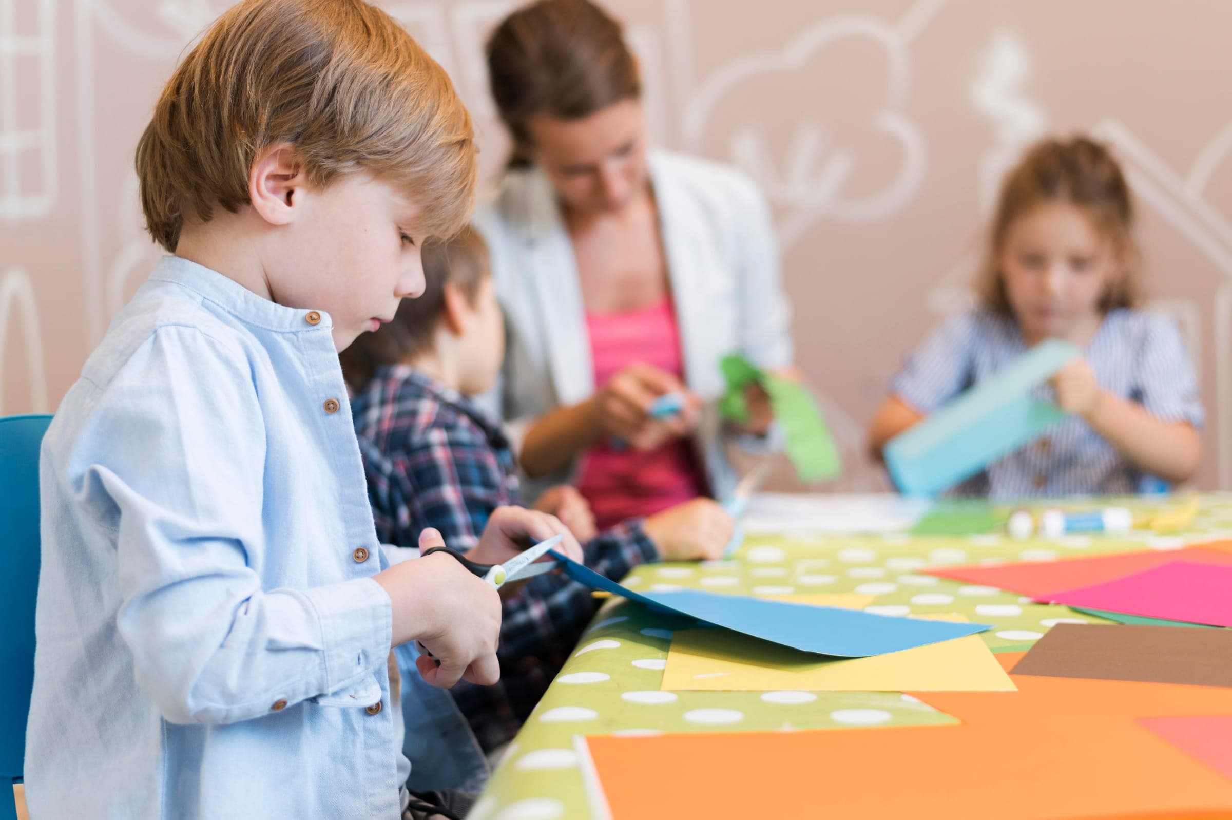 Kinderen knutselen samen met hun juf aan tafel