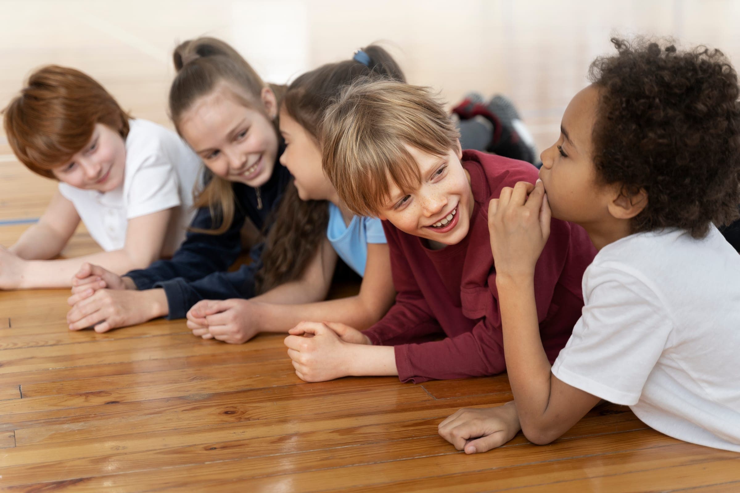 Lachende kinderen liggen samen op de vloer van de gymzaal